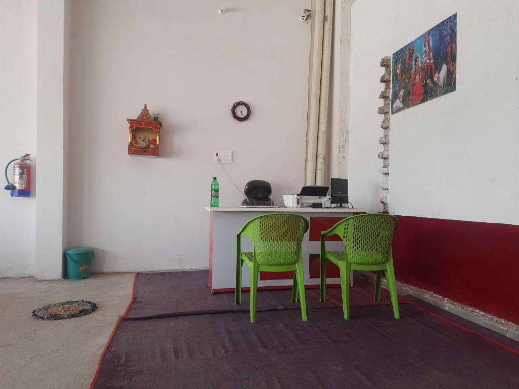 a room with two green chairs and a table at OYO HOME 80891 Hotel Always Welcome in Jewar