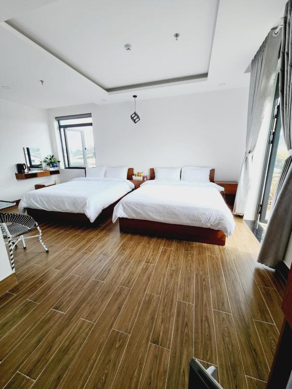 2 camas num quarto amplo com pisos em madeira em Happy Bun Hotel Da Lat em Da Lat