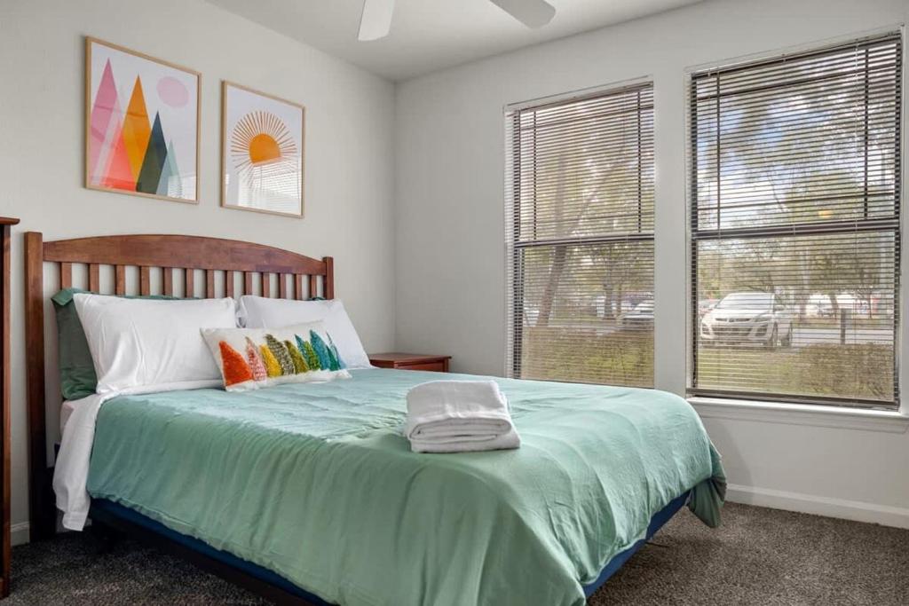 a bedroom with a bed with a green comforter and two windows at Budget Friendly Sleeps 8 Discounts Available in Tampa