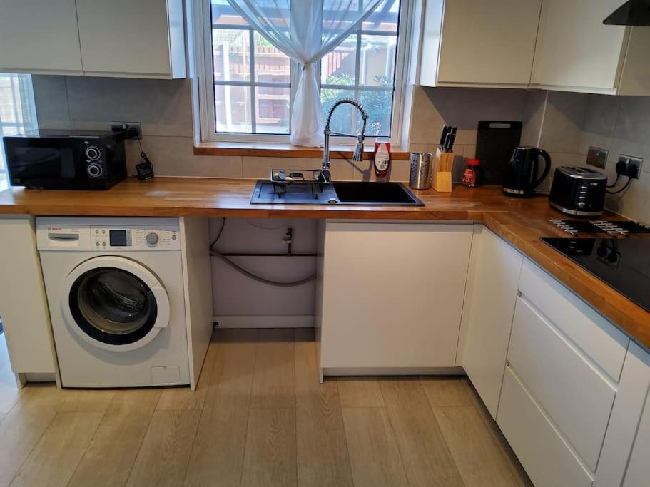 a kitchen with a sink and a washing machine at Primrose lodge cosy 2 bedroom house in a quiet in Norwich