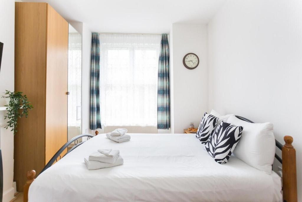 um quarto com uma grande cama branca e um relógio na parede em City Center Camden Market Budget Apartment and Rooms em Londres