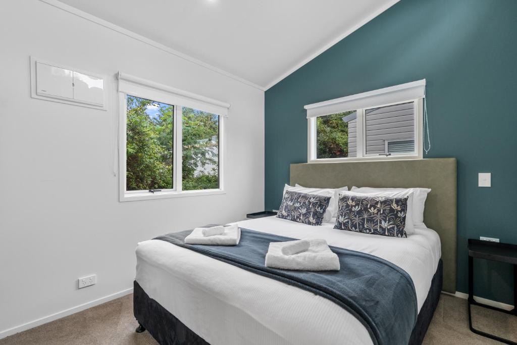 1 Schlafzimmer mit einem großen Bett und 2 Fenstern in der Unterkunft Tasman Holiday Parks - Beachaven in Waihi Beach