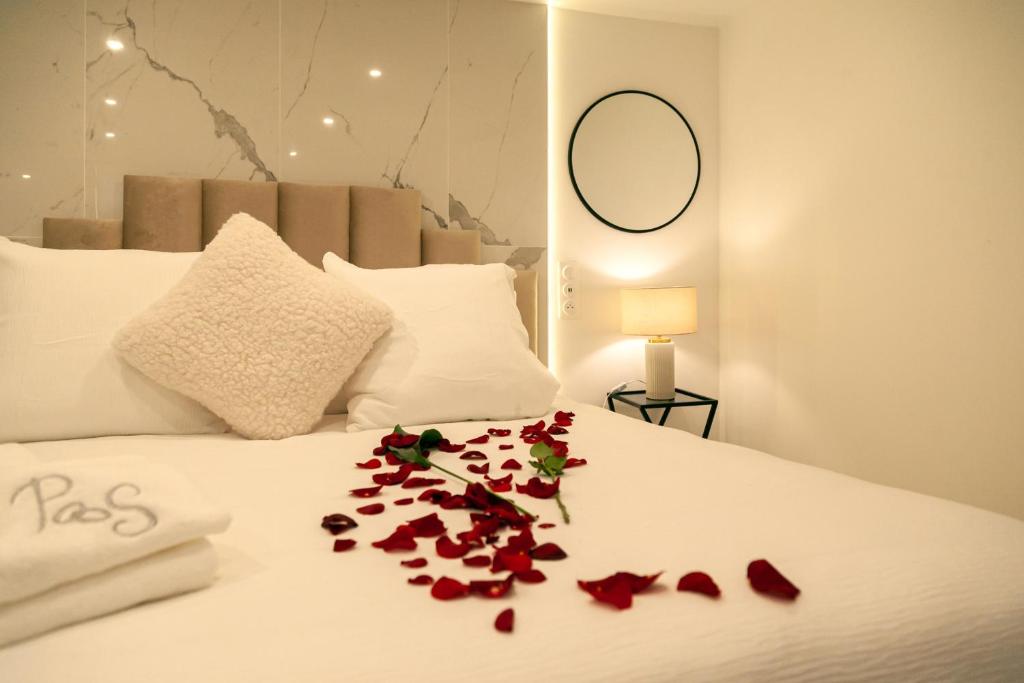 un lit blanc avec des pétales de roses rouges dessus dans l'établissement Maison Panthéon, Suite d'exception, à Meaux