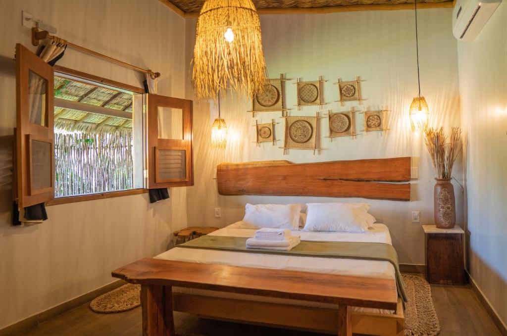 a bedroom with a bed with a table and a window at Rancharia Charme Beach - Pé na Areia in Atins
