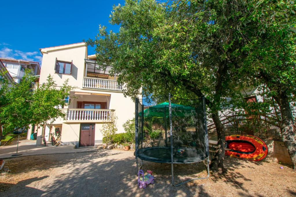 a playground in front of a tree in front of a building at Apartments Barbara in Pakoštane