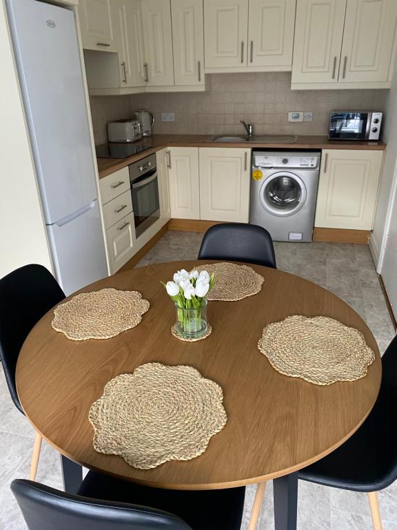 uma cozinha com uma mesa de madeira e cadeiras com flores em Modern comfortable four bedroom house in great location em Dublin