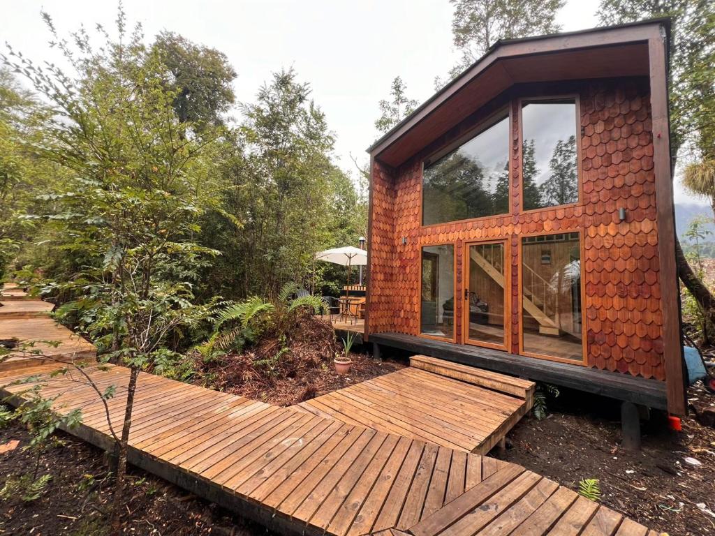 a small house with a wooden deck in the woods at Panigal in Hornopiren