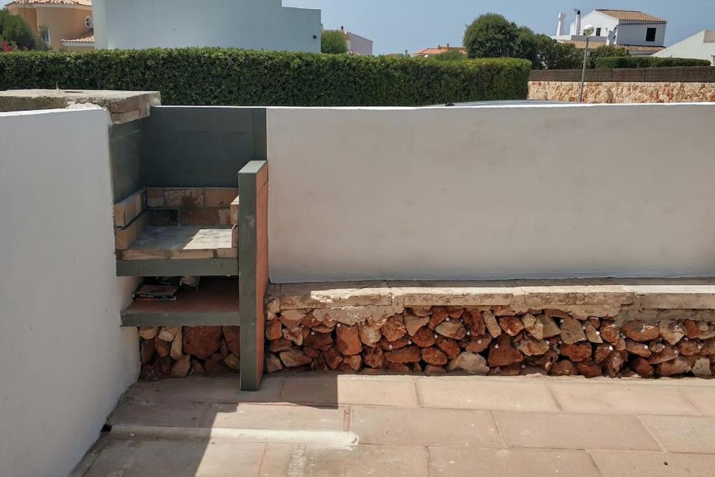 a stone wall with a bench next to a pile of logs at Apartamento con terraza y jacuzzi, zona ciutadella in Cala en Blanes