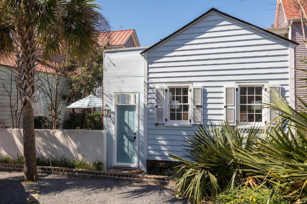 a white house with a blue door and a palm tree at Blue Cottage at Casa Zoe in Charleston