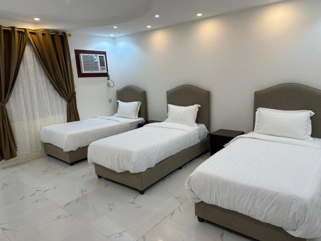 two beds in a hotel room with white sheets at العمري للشقق المفروشة الشهرية in Al Madinah