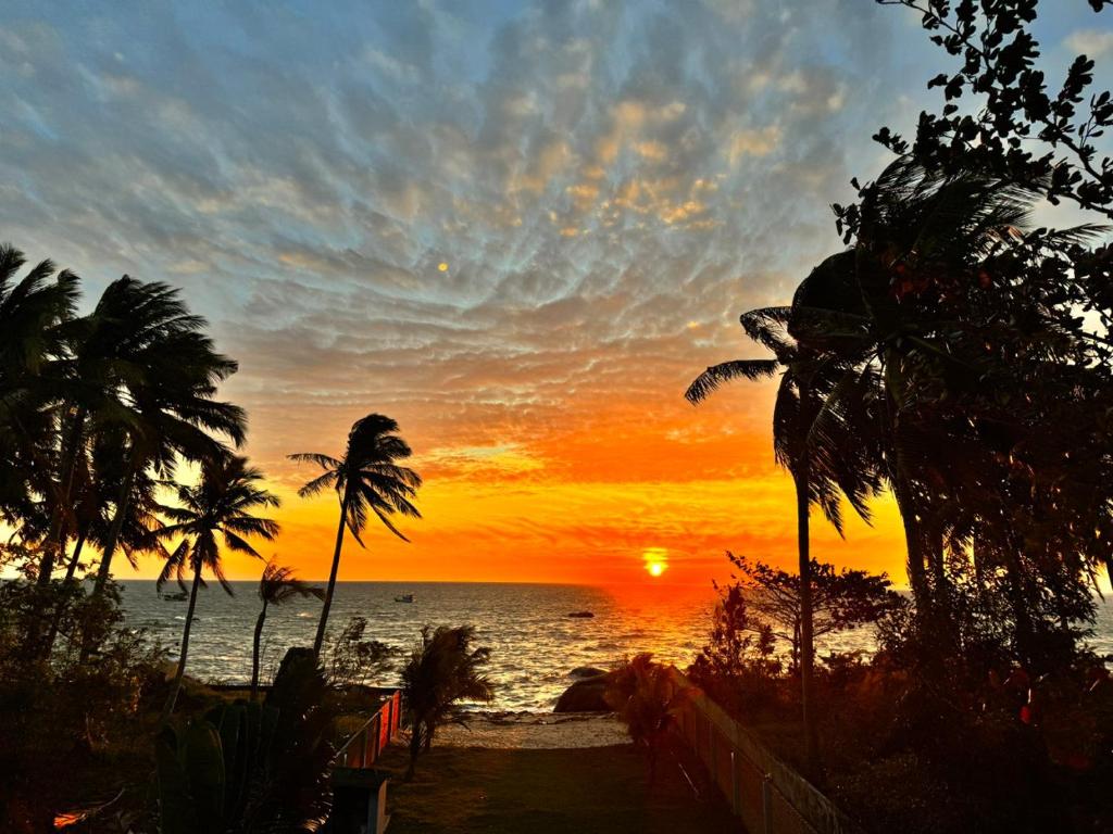 - un coucher de soleil sur la plage avec des palmiers et l'océan dans l'établissement Khalid’s House at the East coast, à Duong Dong