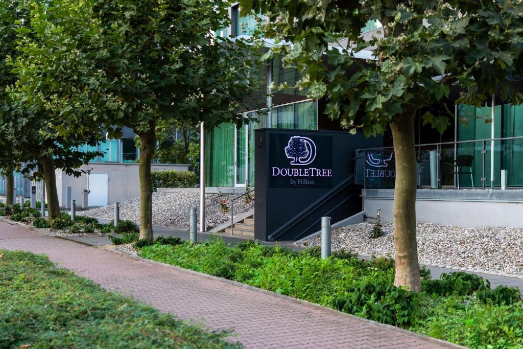um sinal em frente a um edifício com árvores em DoubleTree by Hilton Frankfurt Niederrad em Frankfurt am Main