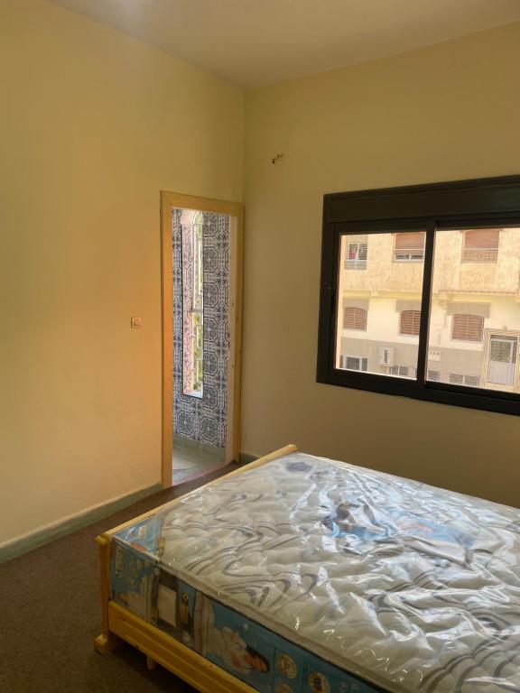 Schlafzimmer mit einem Bett und einem Fenster in der Unterkunft Azrou in Azrou