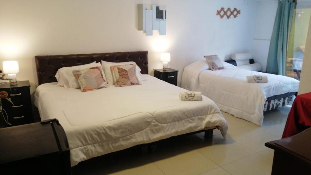 a bedroom with two beds with white sheets and pillows at HOTEL VIEILLE MAISON in Quito