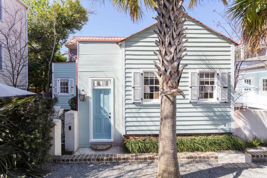 a white house with a palm tree in front of it at Green Cottage at Casa Zoe in Charleston
