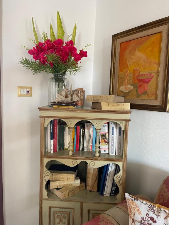 una libreria con un vaso di fiori rossi sopra. di Vittorina's Home a Sorso