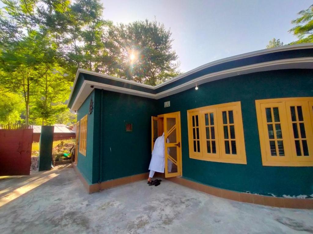 a woman standing in the doorway of a green house at Sharian Guest House in Lamniān