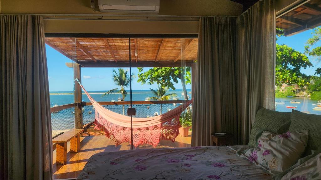 a bedroom with a hammock and a view of the ocean at Casa Aberta in Itacaré