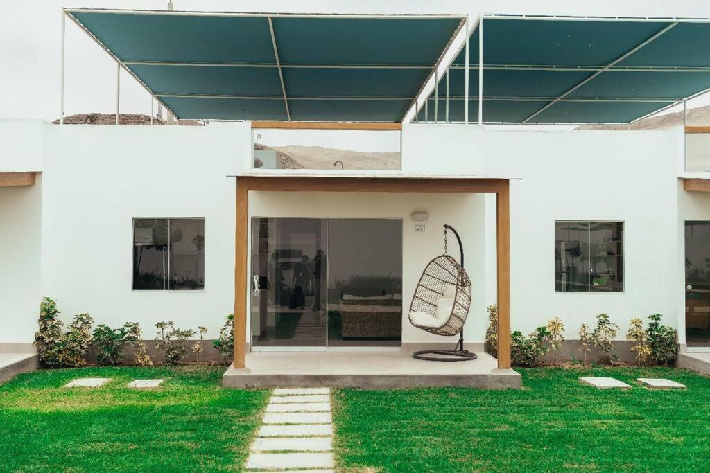 ein weißes Haus mit einem Ventilator auf dem Rasen in der Unterkunft Hermosa casa de playa Balneario Puerto viejo in Salinas