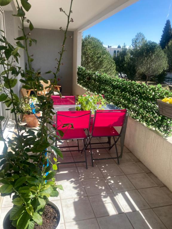 un patio avec des chaises rouges et une table avec des plantes dans l'établissement T2 élégant, à Montpellier