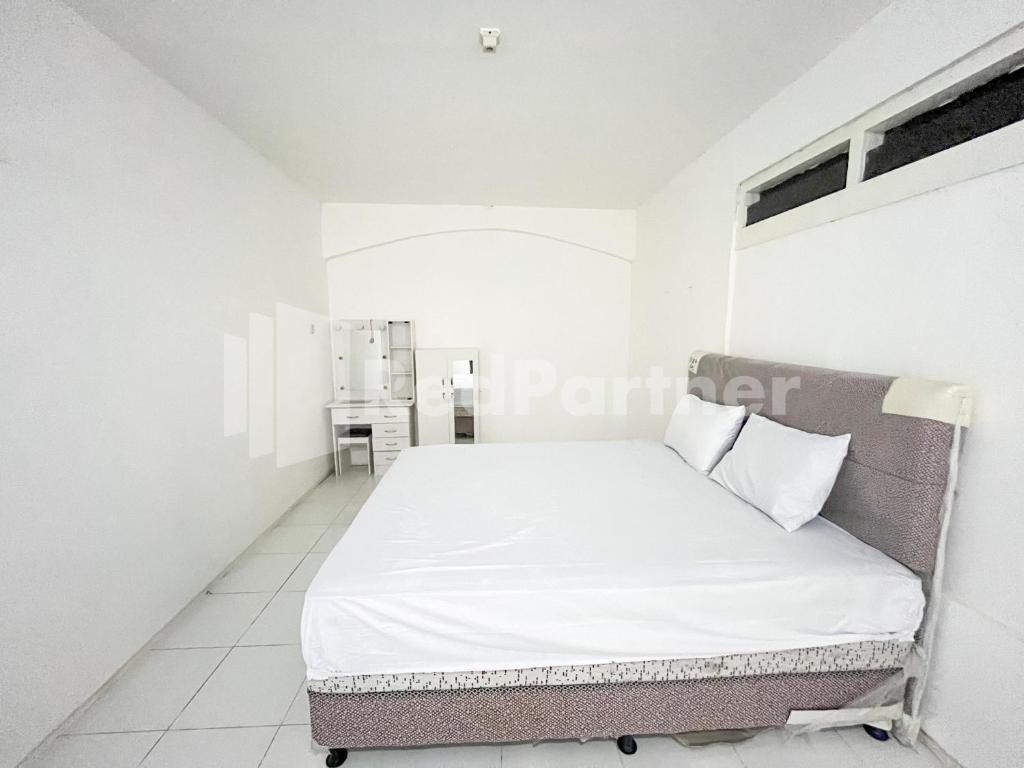 ein weißes Schlafzimmer mit einem Bett mit weißer Bettwäsche und Kissen in der Unterkunft Blessing Syariah Homestay Kediri RedPartner in Kediri