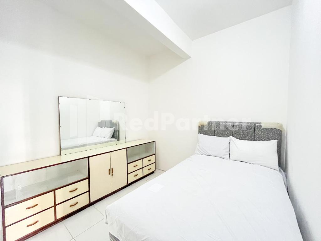 a bedroom with a bed and a dresser with a mirror at Blessings Homestay RedPartner near Stasiun Kediri in Kediri