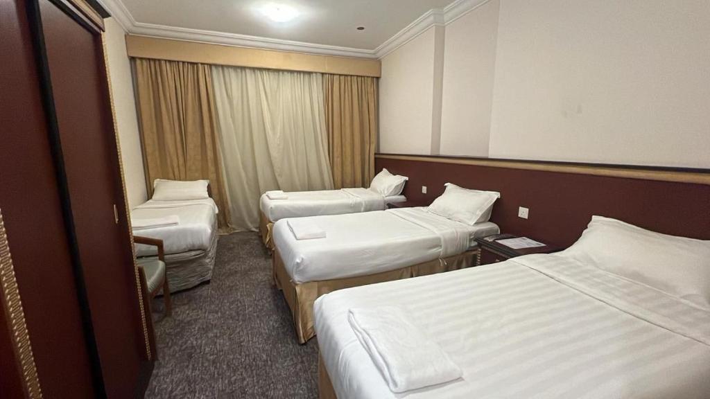 a hotel room with three beds and a chair at فندق رشيد الفضي in Az Zahrāʼ