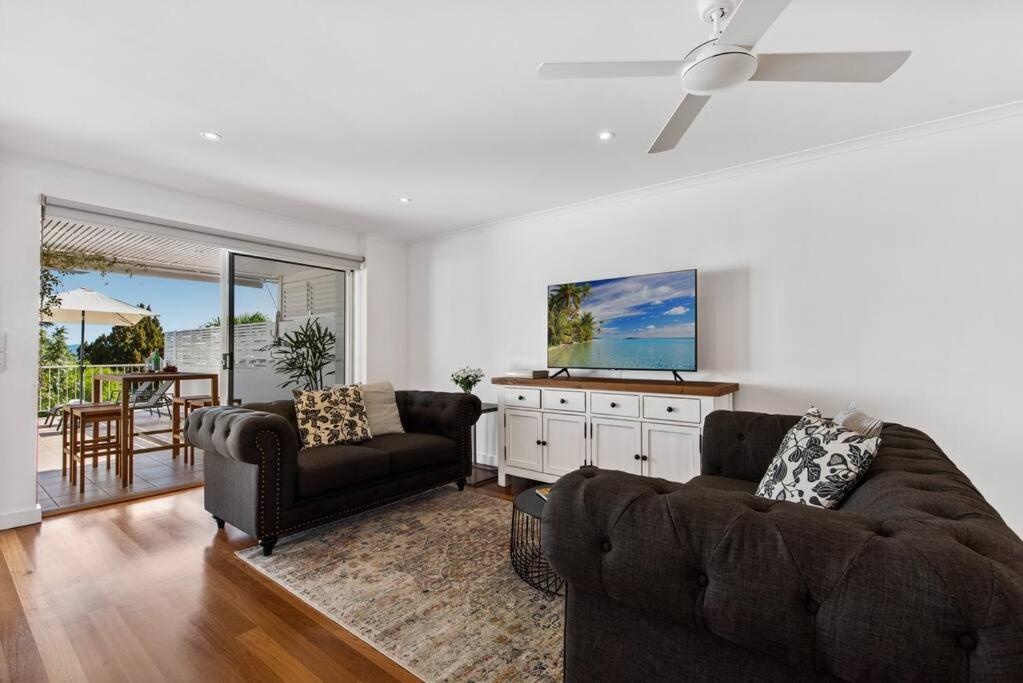 a living room with a couch and a tv at Noosa Tropical Beach Retreat ~ Walk to Everything in Noosa Heads