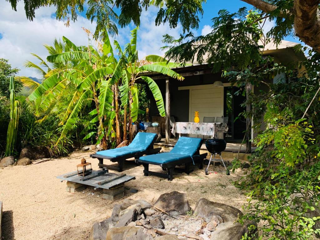 une maison sur la plage avec des chaises bleues et une table dans l'établissement Studio, plunge pool, big garden,beach very close, à Rivière Noire