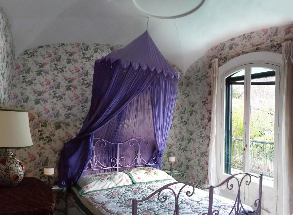 1 dormitorio con 1 cama con dosel púrpura en B&B La Salamandra Kitchengarden, en Isquia