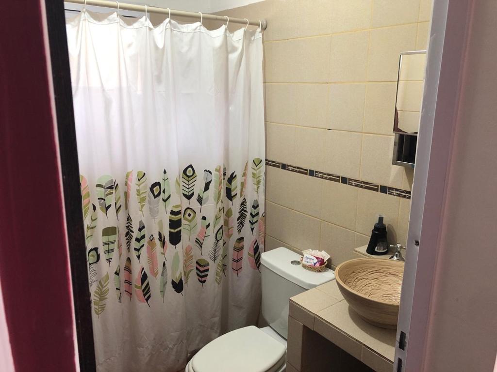 a bathroom with a toilet and a shower curtain at Casitas de Campo Wara kusi in Vaqueros