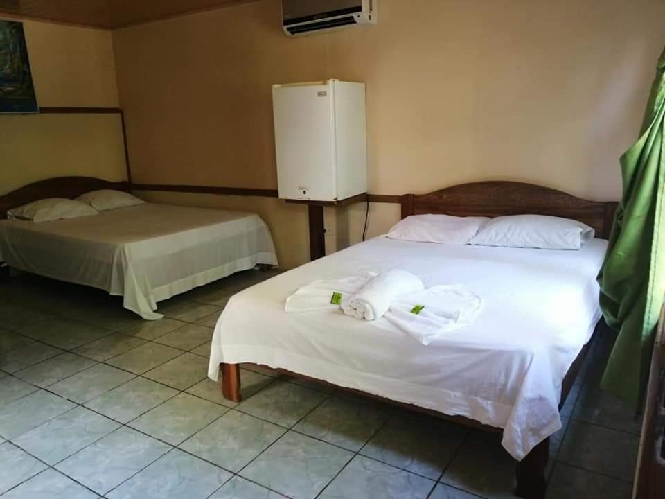 a bedroom with two beds and a refrigerator at Cabinas Valle Azul in San Ramón