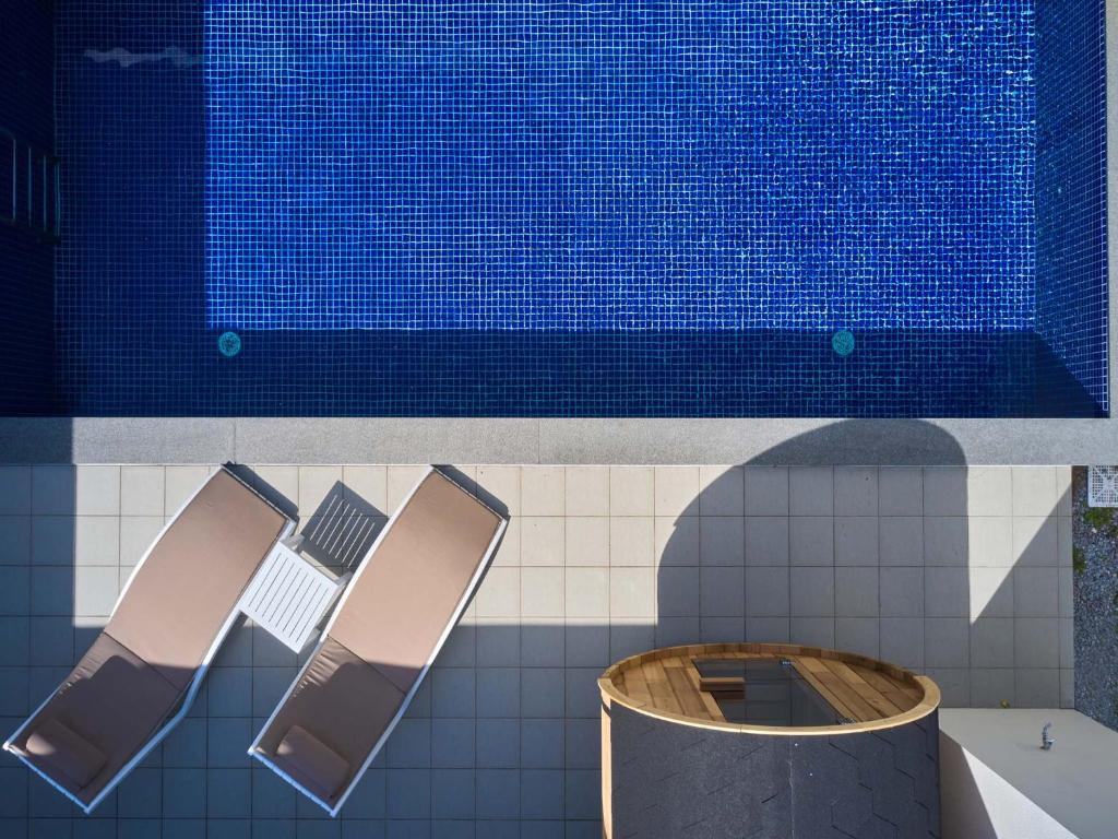 a swimming pool with three chairs next to a swimming pool at The Pool & Sauna Villa MOTOBU in Motobu