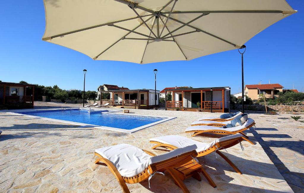 a group of chairs and an umbrella next to a pool at Beautiful Home In Murter in Murter