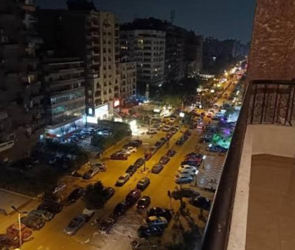 een stadsstraat met auto's geparkeerd op een parkeerplaats bij شقة مفروشة بعباس العقاد in Caïro