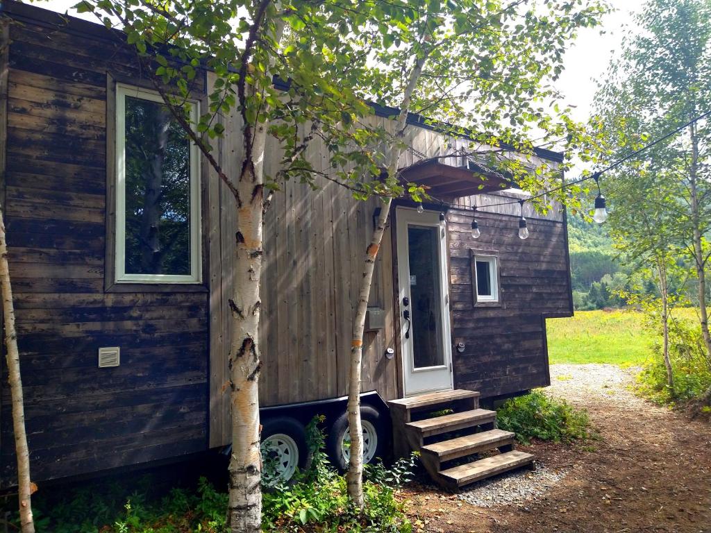 a tiny house is parked next to a tree at Chalets BSL in Saint-Simon-de-Rimouski