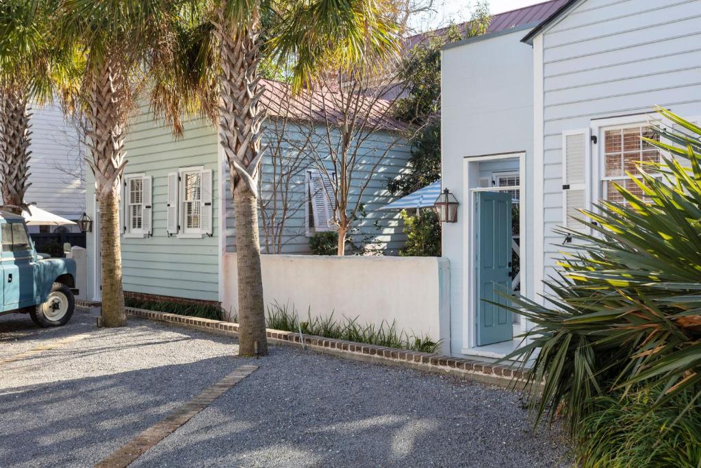a white house with a blue door and palm trees at Cottage Row at Casa Zoe in Charleston