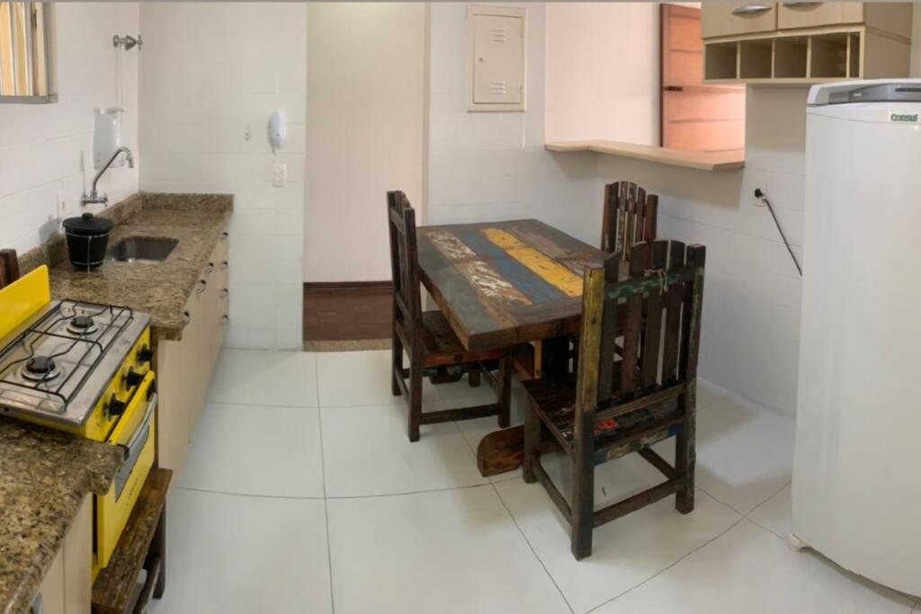 uma cozinha com uma mesa de madeira e cadeiras em Cocal em São Vicente