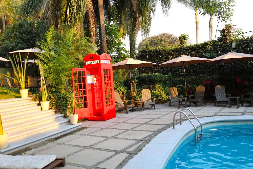 een rode telefooncel naast een zwembad bij Hotel Grand Vista Cuernavaca in Cuernavaca