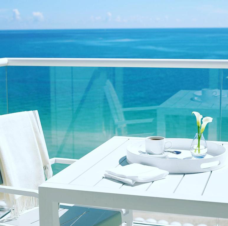 uma mesa branca com um copo e um prato com flores em Thee Ibiza Suites - Ushuaia Beach em Playa d'en Bossa