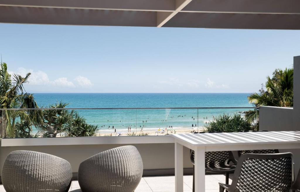 einen Balkon mit Tisch und Stühlen sowie Strand in der Unterkunft Netanya Noosa Beachfront Resort in Noosa Heads