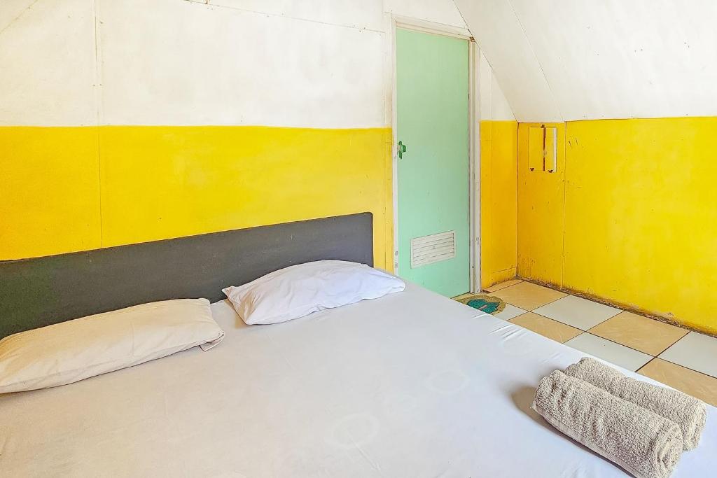 um quarto com uma cama branca com paredes amarelas e verdes em Cigadog Residence Mitra Reddoorz em Ciwidey