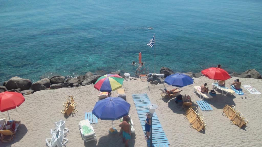 eine Gruppe von Menschen, die am Strand mit Sonnenschirmen sitzen in der Unterkunft Ladikos Beach Hotel in Kardamaina