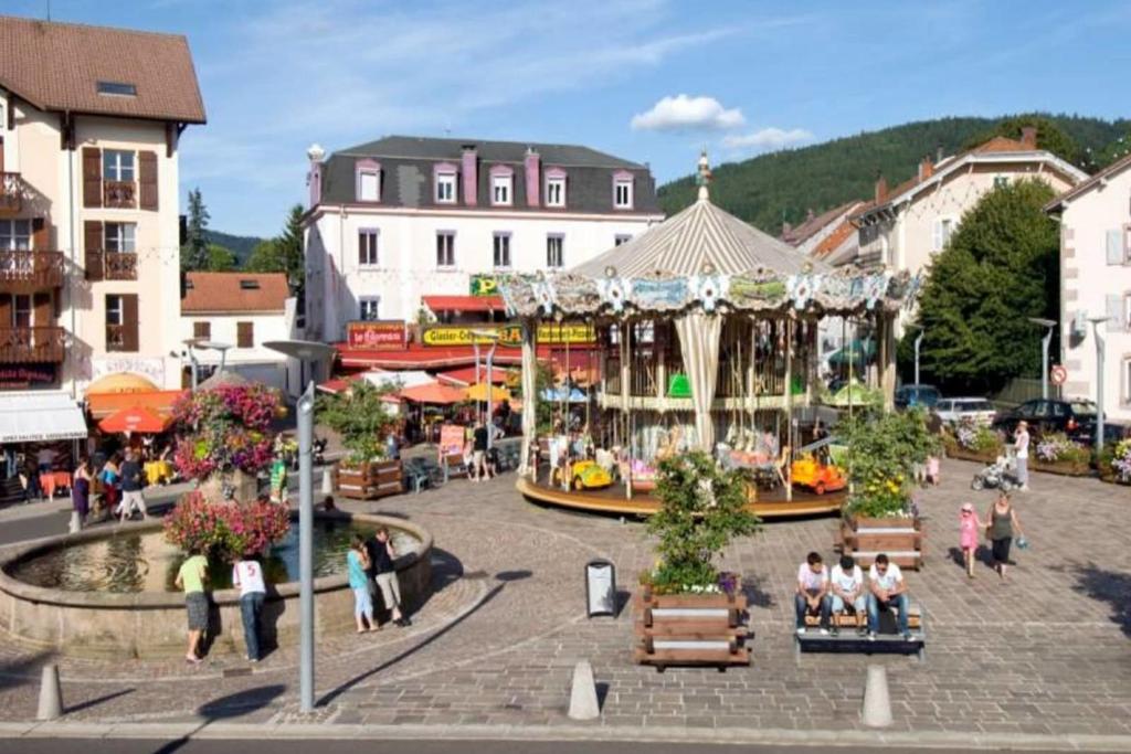 Un groupe de personnes se promenant dans une ville avec un carrousel dans l'établissement Pretty ski nest in the city center, à Gérardmer