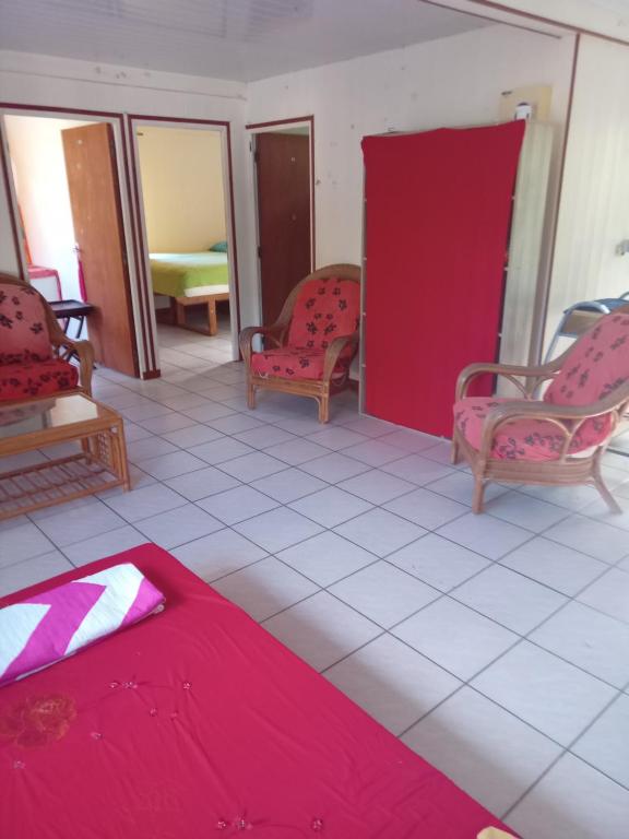 Cette chambre comprend deux chaises et un lit avec des draps rouges. dans l'établissement Heimaruragi home, à Avatoru