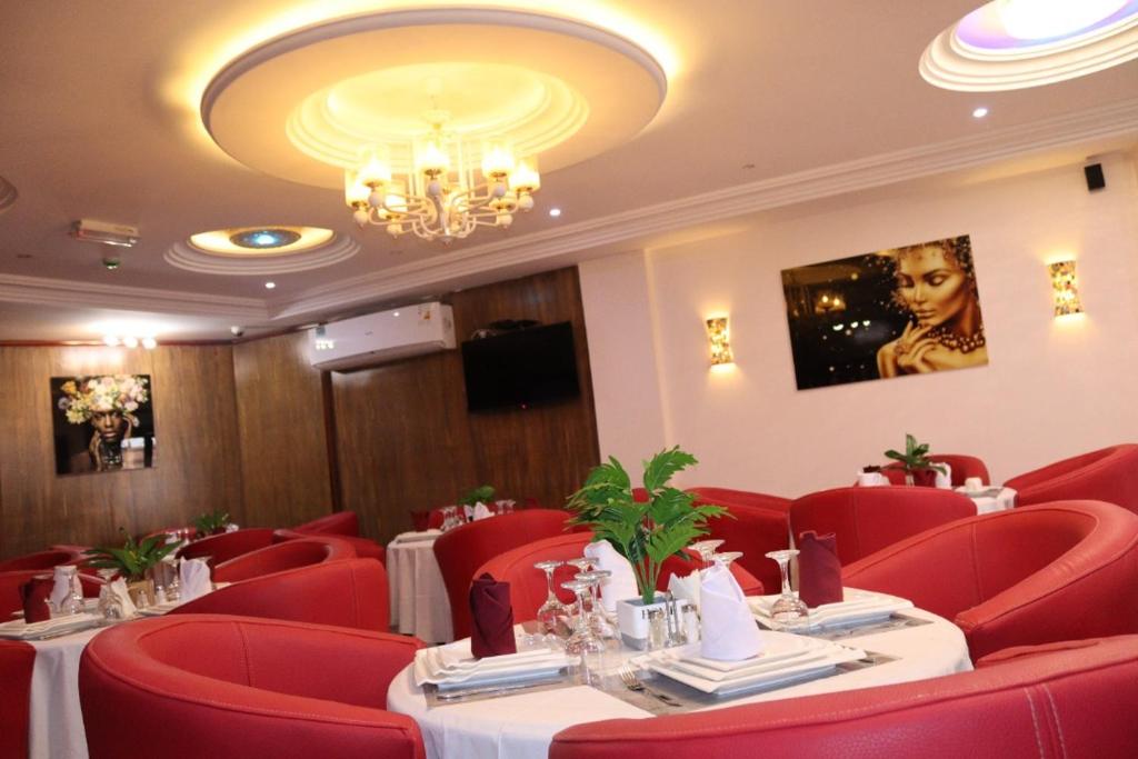 un restaurante con sillas y mesas rojas y una lámpara de araña en Matcheu palace Hôtel en Yaundé