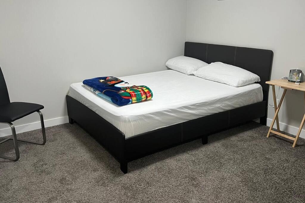 a bed with a black headboard and a blanket on it at Not-Available - Do not book please in Airdrie