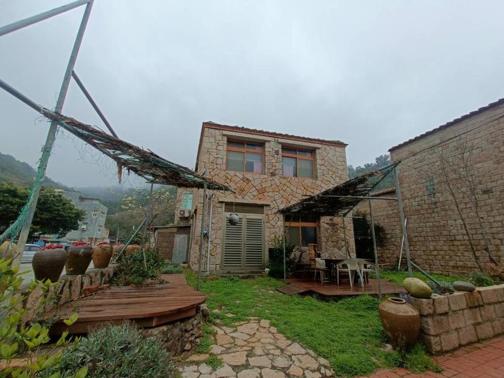 a stone house with a patio and a building at 馬祖津沙背包客棧-Jinsha backpacker inn in Nangan