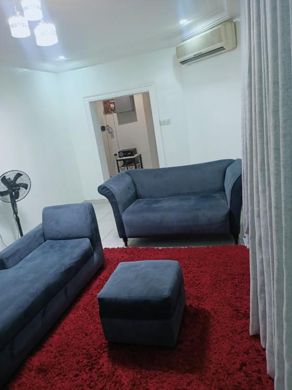 a living room with two blue couches and a red rug at Sommy's place in Abuja