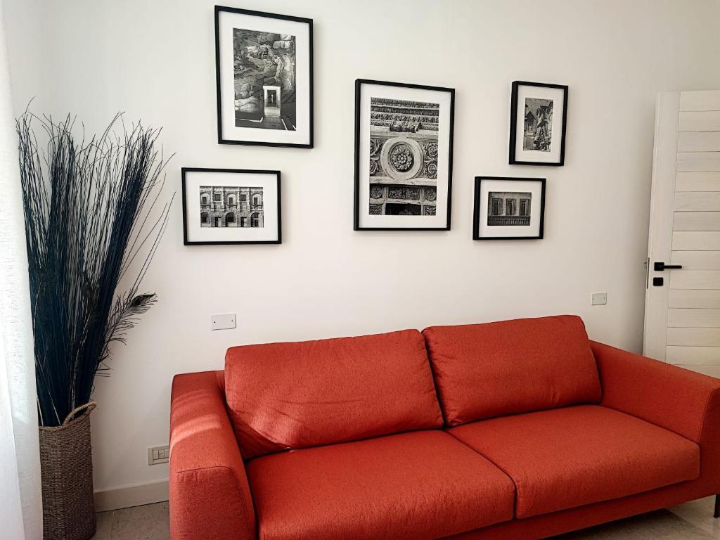 um sofá vermelho numa sala de estar com fotografias na parede em Foresteria Juvarra em Mantova